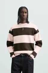 Jersey de punto con diseño de rayas horizontales anchas en color rosa claro y marrón oscuro. Presenta cuello redondo, manga larga y terminaciones en rib.