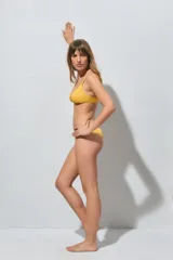 Top de bikini amarillo con textura sutil y detalle de aros metálicos entrelazados en el centro del escote, con tirantes finos.