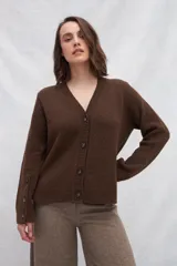 Cárdigan color crema de tejido de punto industrial con escote en V, combinación de puntos y botones decorativos en las mangas.