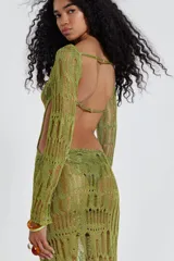 Vestido largo de tejido de punto calado color dorado, con espalda descubierta y mangas largas.