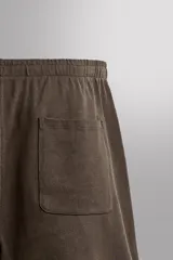 Short jogger marrón de corte relaxed fit, confeccionado en tejido compacto de algodón, con cintura elástica ajustable, bolsillos frontales en la cadera y bolsillo trasero de plastrón.