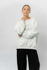 Buzo oversize de algodón frizado color beige, con cuello redondo, puños y cintura tejidos. Presenta un bordado tono sobre tono de Garfield en el frente.
