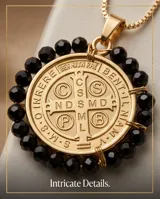 Collar de acero con baño de oro, con cadena fina y medalla colgante de San Benito rodeada por cristales negros facetados.