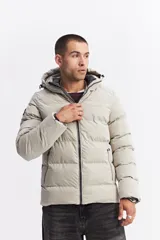 Campera puffer con capucha, diseño acolchado, cierre frontal y bolsillos laterales. Presenta un interior en contraste de color verde oliva.