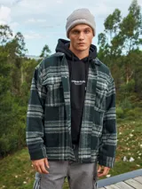 Sobrecamisa a cuadros verde oscuro, marrón y blanco, de manga larga con puños abotonados, cierre frontal con botones y bolsillos en el pecho.
