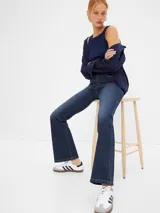 Jean de tiro alto con corte flare, confeccionado en denim de lavado oscuro con costuras en contraste.