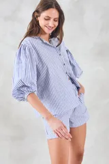 Camisa celeste a rayas verticales blancas, de corte holgado y mangas 3/4 abullonadas.