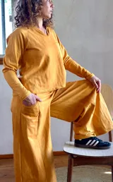 Conjunto de dos piezas compuesto por un buzo de cuello en V con bolsillo frontal y un pantalón tipo palazzo de corte evasé y pierna ancha. Confeccionado en tejido rústico de algodón con efecto batik.