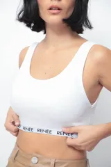 Top corto de morley color blanco, con escote redondo y elástico personalizado con el nombre de la marca en el bajo busto.