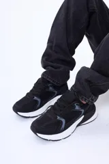 Championes urbanos de diseño deportivo, combinando paneles de malla y cuero sintético en color negro con detalles en gris. Presentan una suela gruesa de goma blanca con diseño ergonómico y cierre mediante cordones al tono.