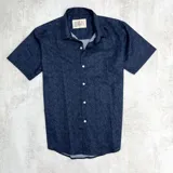 Camisa de manga corta azul con estampado floral, cuello clásico y cierre frontal con botones.