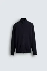 Chaqueta de punto de algodón con textura perlada, corte regular fit, cuello subido y cierre frontal con cremallera. Presenta mangas largas con puños y ruedo en rib.