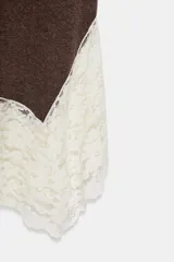 Vestido largo de cuello perkins y diseño sin mangas, confeccionado en tejido de punto color marrón. Presenta un bajo con corte evasé y detalle de encaje en color crudo a contraste. Cierre posterior con cremallera oculta.