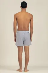 Short de baño con rayas verticales azules y blancas, pretina elastizada con cordón ajustable, bolsillos laterales y traseros con cierre.