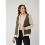 Chaleco estilo gamulán en color verde militar, con forro interior y bordes de corderito sintético en tono crema. Presenta un diseño sin mangas, ideal para usar sobre prendas de abrigo.