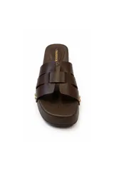 Sandalia tipo zueco Paddock de color negro, con plataforma baja de aspecto amaderado y tiras entrelazadas en el empeine. Presenta detalles de tachas metálicas doradas en los laterales y plantilla acolchada.