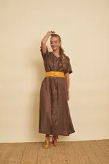 Vestido midi de lino marrón, de corte túnica y manga corta, con detalles de volados verticales a lo largo de la botonera frontal y bolsillos en los costados.