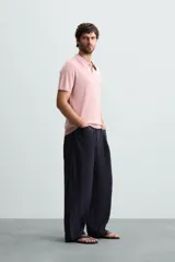 Polo de punto canalé color rosado, de corte regular fit, con cuello solapa y cierre frontal de botonadura. Manga corta y acabados en rib.