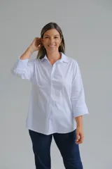 Camisa de corte clásico en color blanco, con cuello camisero, cierre frontal de botones y mangas largas con puños abotonados.