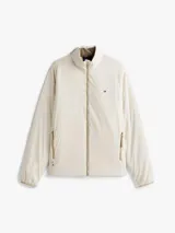 Campera ligera color crema, con cuello alto y cierre frontal de cremallera. Presenta un pequeño logo bordado de Tommy Hilfiger en el pecho.