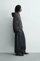 Chaqueta de punto de corte relajado, color azul, con capucha, cierre frontal con cremallera y acabados en rib en puños y bajo.