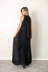Enterito largo de lurex plisado color negro, con escote halter y corte amplio en las piernas. Incluye un cinturón metálico decorativo en la cintura.
