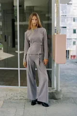Pantalón de tiro alto con pierna ancha, confeccionado en sarga color tostado. Presenta detalle de doble hilera de botones metálicos dorados en el frente y pinzas verticales.