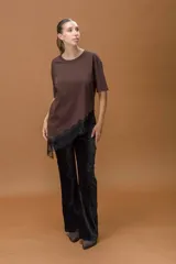 Pantalón de corte oxford confeccionado en pana negra con textura aterciopelada. Presenta un ajuste en la cadera y muslos, con una leve apertura desde la rodilla hacia el ruedo.