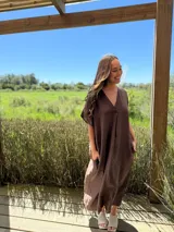Vestido de lino color marrón oscuro, con escote en V, mangas cortas y corte relajado con bolsillos amplios.