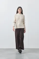 Polera de tejido de punto color marrón, con cuello alto y diseño de textura con relieves y trenzas. Posee mangas largas con puños acanalados.