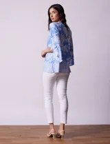 Blusa color salmón con estampado floral blanco, cuello redondo con abertura y mangas 3/4 acampanadas.