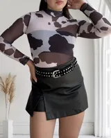 Body de tul traslúcido con estampado de manchas de vaca en blanco y negro, cuello alto y mangas largas.