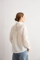 Camisa celeste con apliques florales bordados, cuello camisero, manga larga y cierre frontal de botones.
