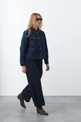 Campera de jean color negro con cuello de pana en tono marrón, cierre frontal con botones metálicos y bolsillos frontales tipo cargo.