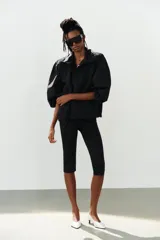 Mono de poliamida color negro con escote halter y escote en V profundo, de corte ajustado y largo por encima de la rodilla.