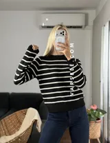 Sweater de punto con diseño de rayas horizontales negras sobre fondo blanco, cuello redondo y puños y ruedo acanalados.