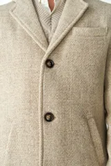 Abrigo masculino de lana color beige, con cuello con solapa, manga larga y forro interior. Tiene bolsillos laterales y cierre frontal con botones.