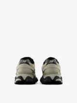 Championes urbanos New Balance modelo 9060, de color gris y beige con detalles en negro. Presentan un diseño robusto y futurista inspirado en la era Y2K, con entresuela gruesa esculpida y el característico logotipo "N" en el lateral.