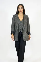 Blazer de corte entallado en color gris con textura jaspeada, solapas clásicas, bolsillos laterales y mangas con vuelta en contraste negro.