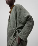 Blusa verde oliva de tejido arrugado con poliéster reciclado. Escote pico, manga japonesa, delantero cruzado y ata lateralmente con tira estrecha del mismo tejido.