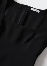 Vestido corto entallado de color negro, con escote cuadrado y mangas largas. Cuenta con cierre de cremallera en la parte posterior.