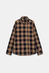 Camisa de manga larga con estampado de cuadros en tonos marrón y negro. Presenta un diseño cruzado con cuello vuelto y cierre frontal de botones, con un corte asimétrico en el bajo.