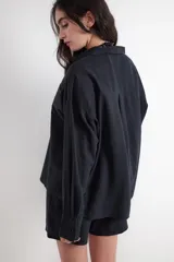 Camisa de manga larga color negro, de corte holgado, cuello camisero, cierre frontal con botones y un bolsillo aplicado en el pecho. Confeccionada en mezcla de lino y viscosa.