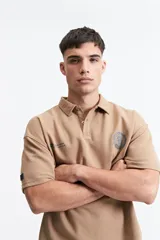 Remera polo color crema con logo bordado en el pecho, de corte amplio y mangas cortas.