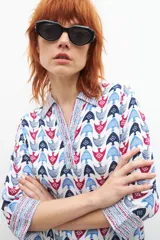 Blusa de manga larga con cuello camisero y estampado con motivos geométricos en tonos azul, rojo y blanco.