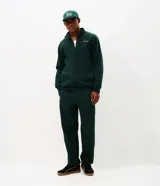 Pantalón deportivo de corte recto color verde oscuro, confeccionado en tejido de algodón y poliéster. Cuenta con cintura elástica con cordón ajustable, bolsillos laterales funcionales y una cinta decorativa lateral.