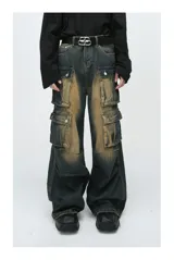 Pantalón de jean ancho (baggy) con lavado oscuro y efecto desgastado en tonos marrones/ocre. Presenta múltiples bolsillos cargo grandes con tapa y botones a presión en las piernas.