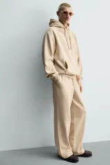 Pantalón jogger de corte relajado y pernera ancha, confeccionado en tejido de algodón con interior perchado. Presenta cintura elástica con cordón interior, bolsillos laterales y un bolsillo trasero de plastrón.
