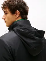 Campera acolchada negra, con cuello alto y cierre frontal de cremallera. Presenta bolsillos laterales con cierre y el logo de Tommy Hilfiger bordado en el pecho.