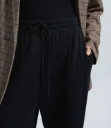 Pantalón de corte wide leg confeccionado en algodón con felpa, color marrón topo. Presenta cintura elástica con cordón ajustable y costuras verticales decorativas en el frente.